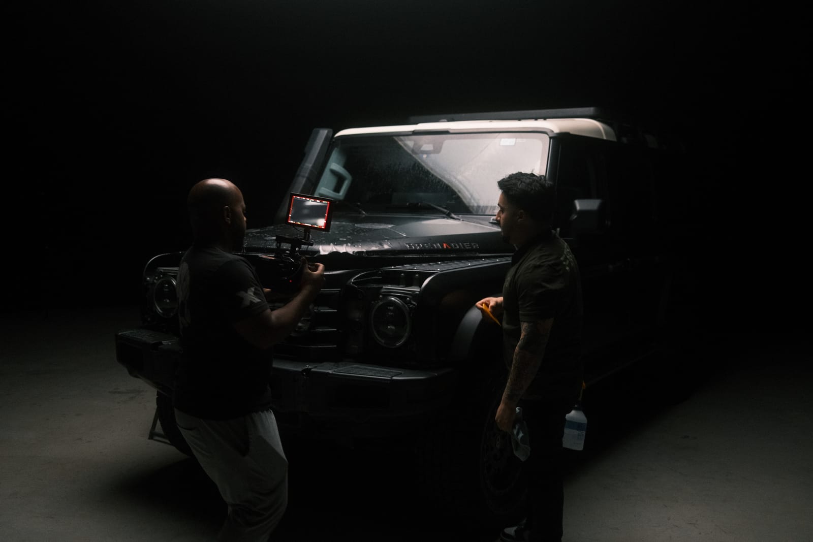 Two crew members setting up a camera rig on the hood of a four wheel drive vehicle inside the studio